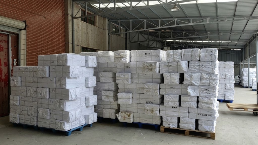 PP Woven Bags are shown stacked in a warehouse, illustrating their use for protecting cartons during storage, handling, and transportation.