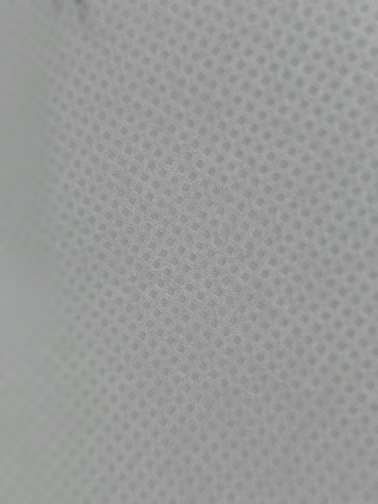 Close-up of white non-woven fabric with a dotted bonding pattern.