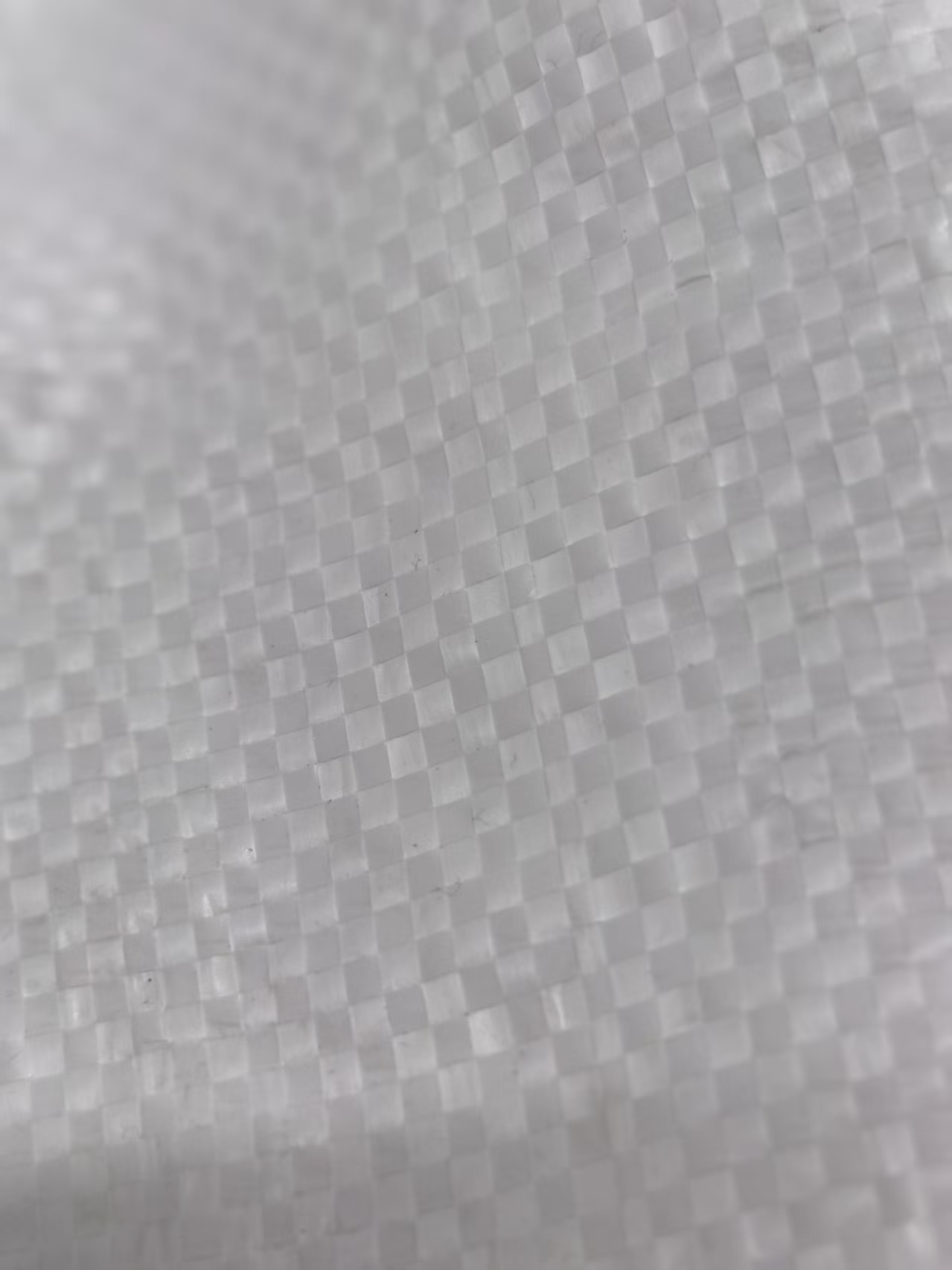 Close-up of white PP woven fabric showing interlaced plastic tapes.
